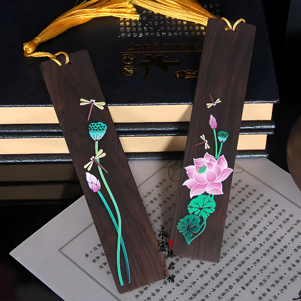 Close-up of a hand-painted lotus design on a polished sandalwood Chinese bookmark with hanging cord.