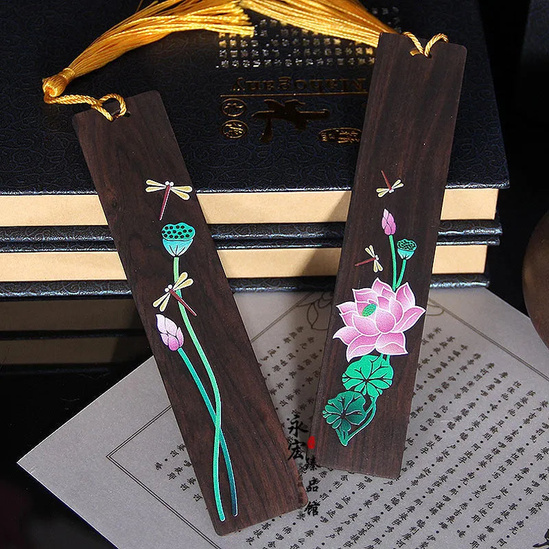 Close-up of a hand-painted lotus design on a polished sandalwood Chinese bookmark with hanging cord.