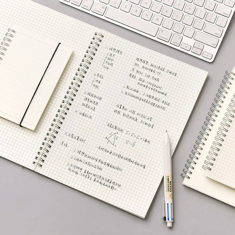 B5 coil grid notebook with Pp cover, open showing lined pages on a desk