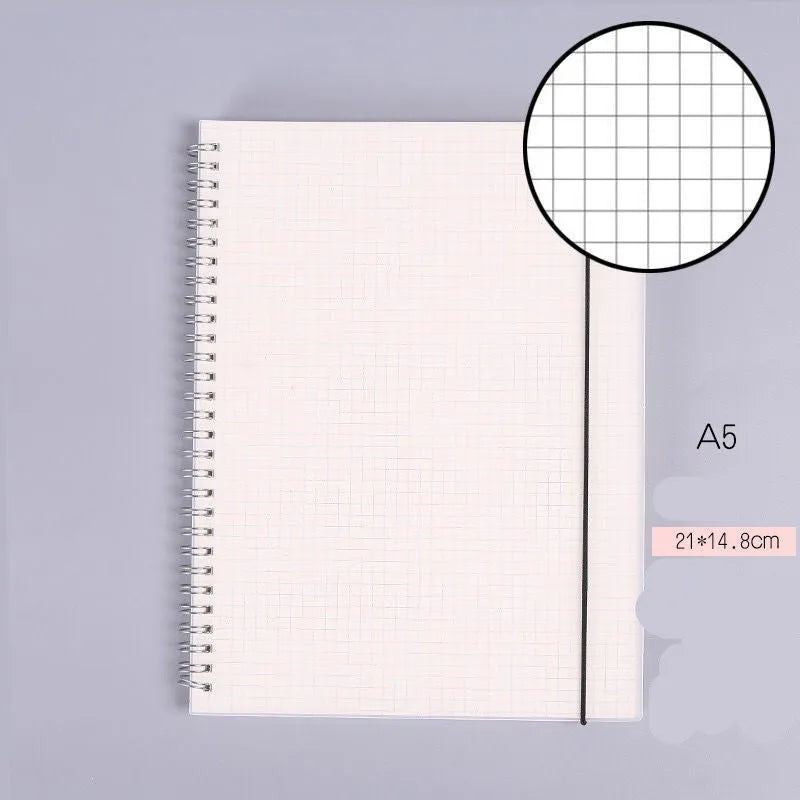 B5 coil grid notebook with Pp cover, open showing lined pages on a desk