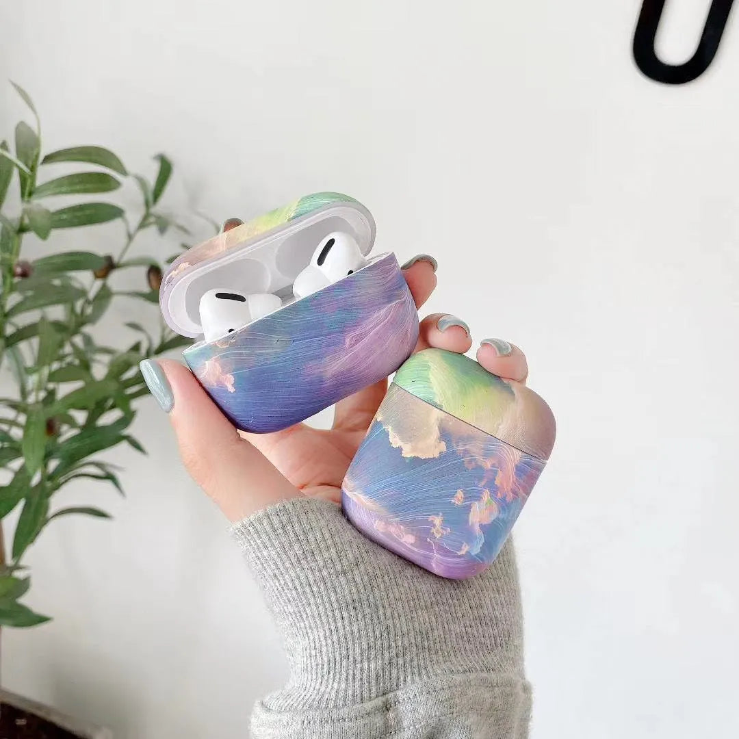 Hard plastic protective sleeve for AirPods case in a pink watercolour design, shown next to a blue watercolour version.