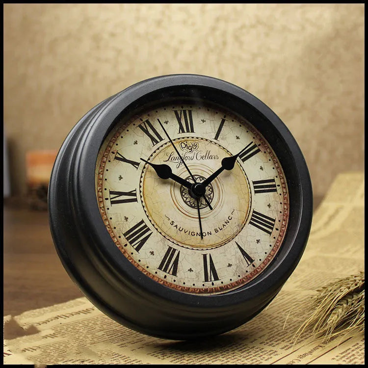 Round retro desk alarm clock with a white dial on a wooden surface.