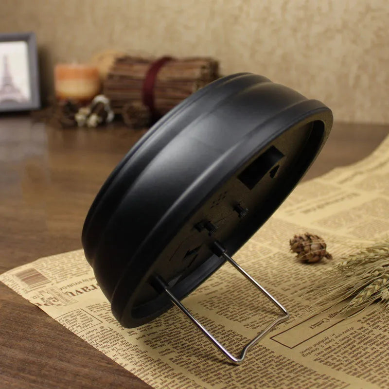 Round retro desk alarm clock with a white dial on a wooden surface.