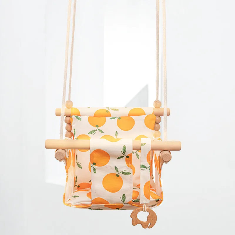 Natural beige cotton canvas baby swing chair with wooden seat and tassel pattern, hanging indoors.