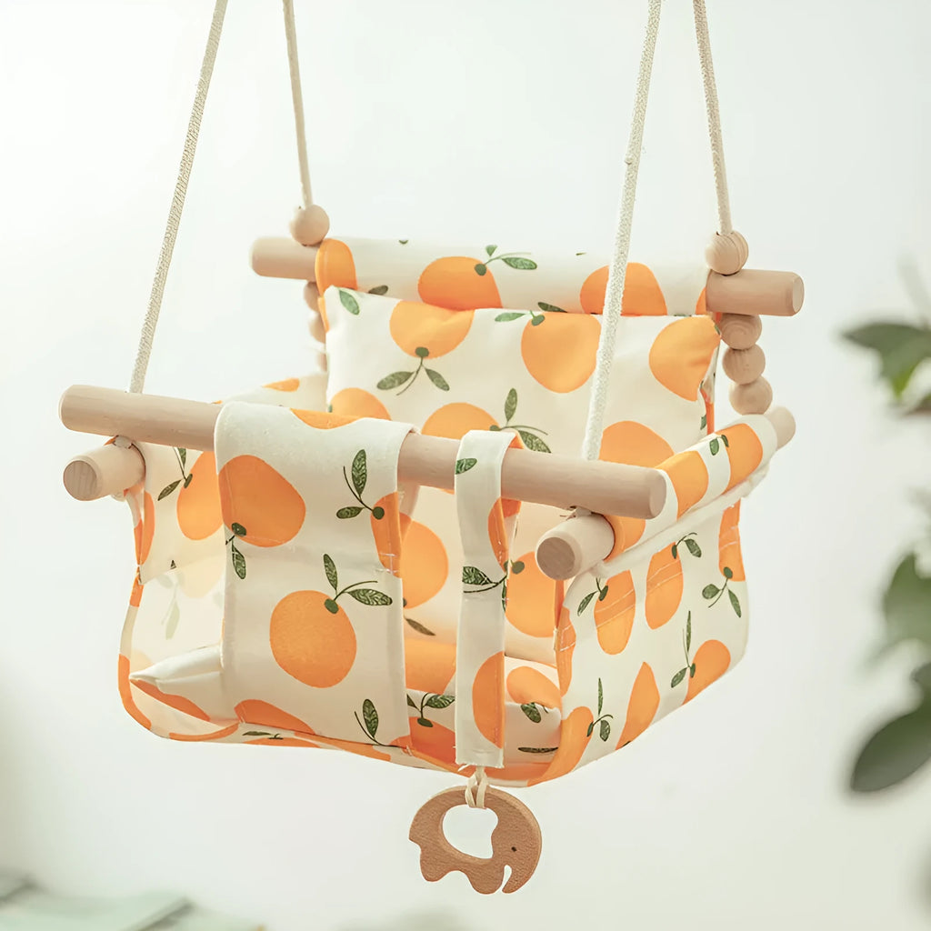 Natural beige cotton canvas baby swing chair with wooden seat and tassel pattern, hanging indoors.