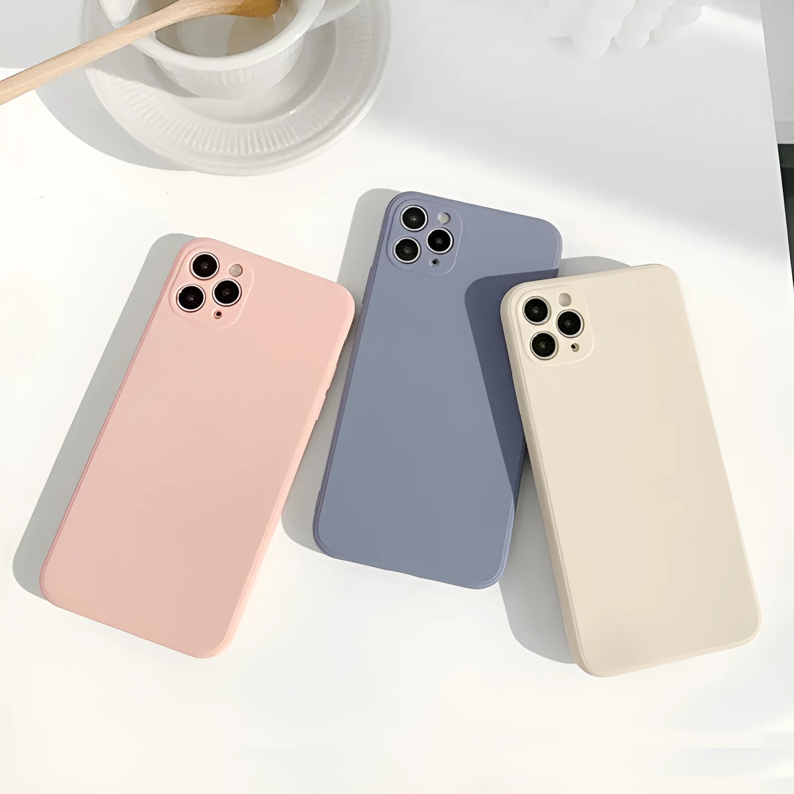 Simple solid colour silicone phone case for iPhone in pink, blue, and antique white options.