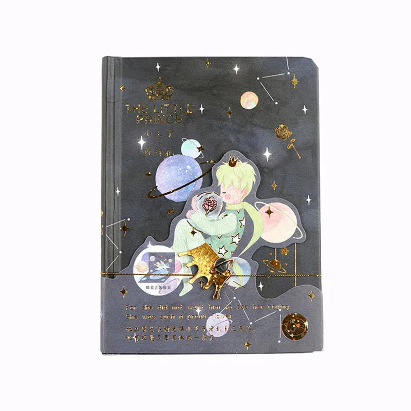 Hardback notebook with The Little Prince design cover, open to show saddle stitch binding and blank pages.