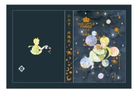 Hardback notebook with The Little Prince design cover, open to show saddle stitch binding and blank pages.