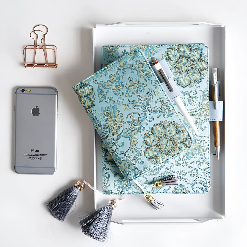 Flying blue flowers pattern fabric cover notebook in A5 and A6 sizes on a desk.
