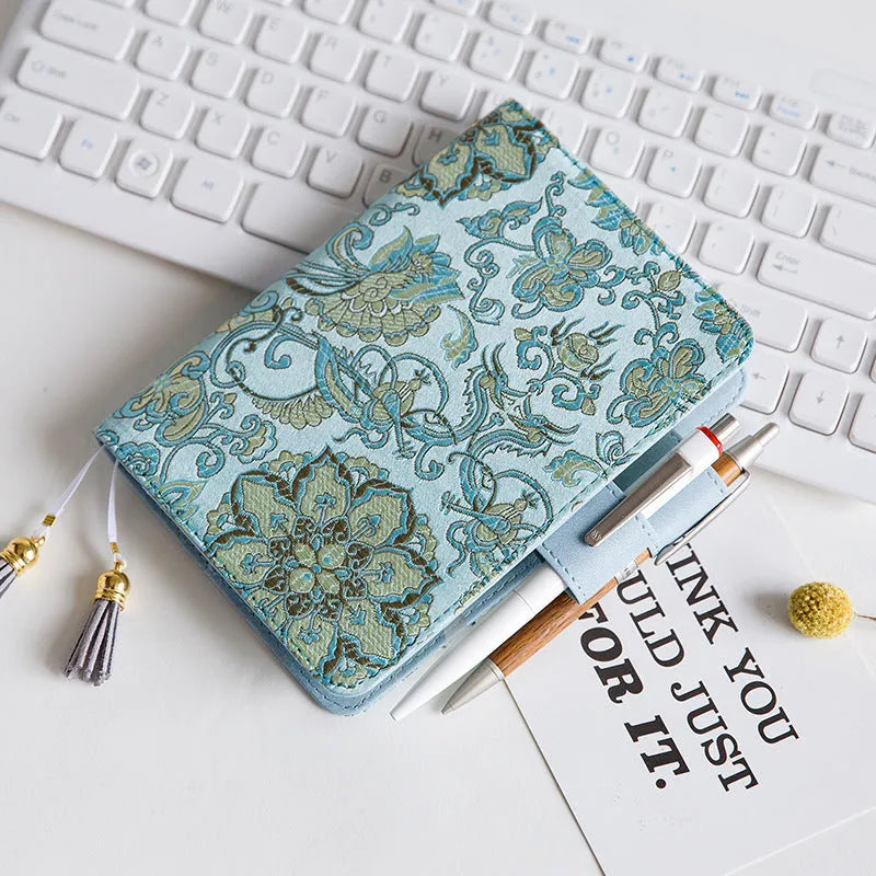 Flying blue flowers pattern fabric cover notebook in A5 and A6 sizes on a desk.