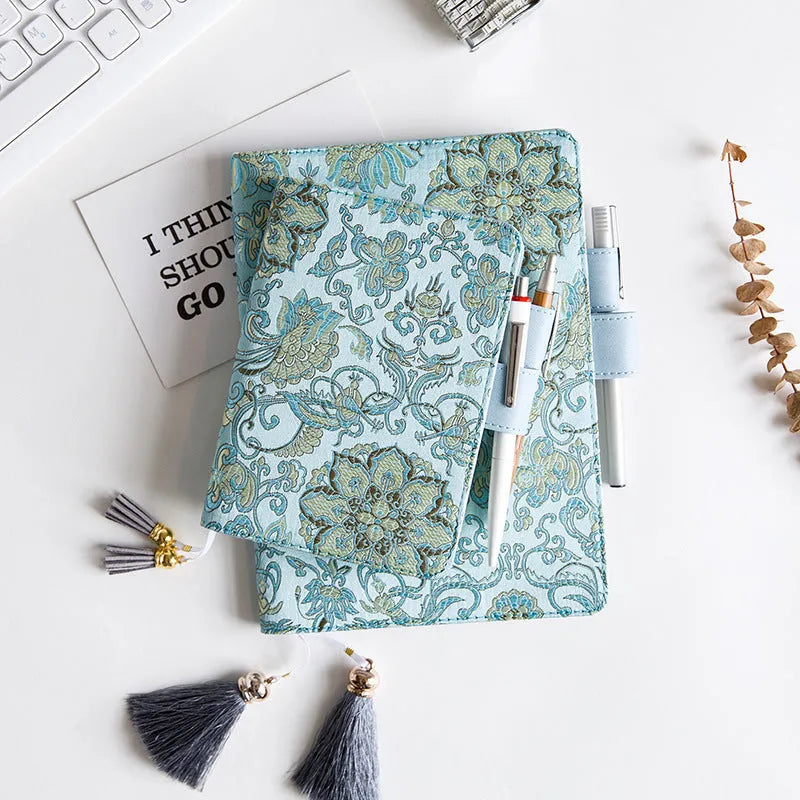 Flying blue flowers pattern fabric cover notebook in A5 and A6 sizes on a desk.
