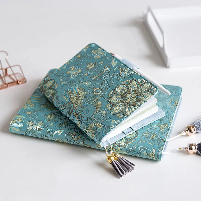 Flying blue flowers pattern fabric cover notebook in A5 and A6 sizes on a desk.