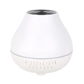 White round Bluetooth aroma diffuser and humidifier unit with night light on a wooden surface.