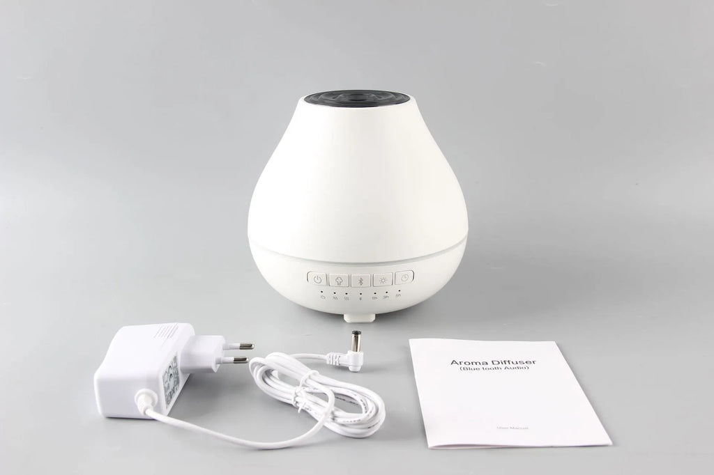 White round Bluetooth aroma diffuser and humidifier unit with night light on a wooden surface.