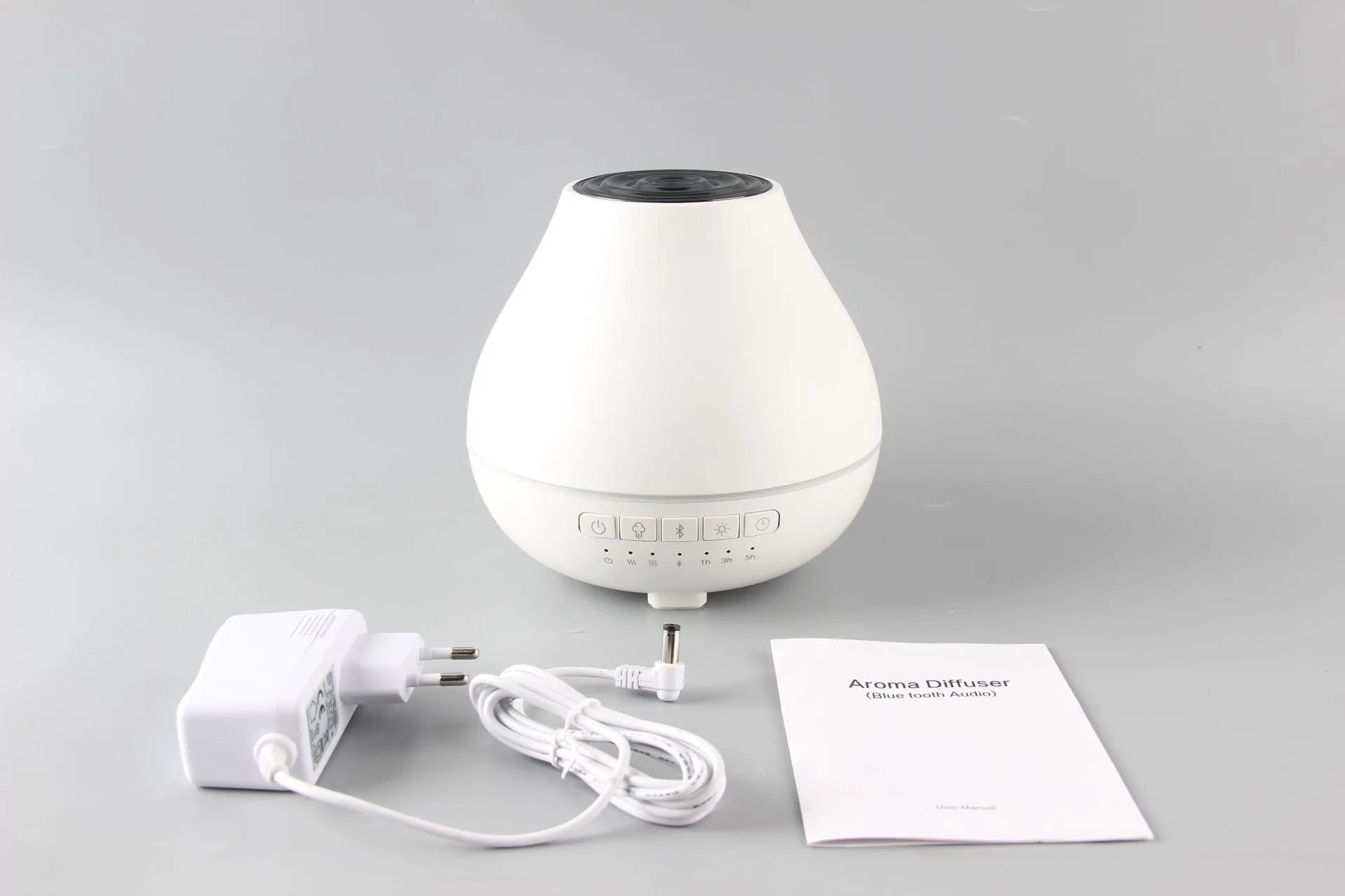 White round Bluetooth aroma diffuser and humidifier unit with night light on a wooden surface.