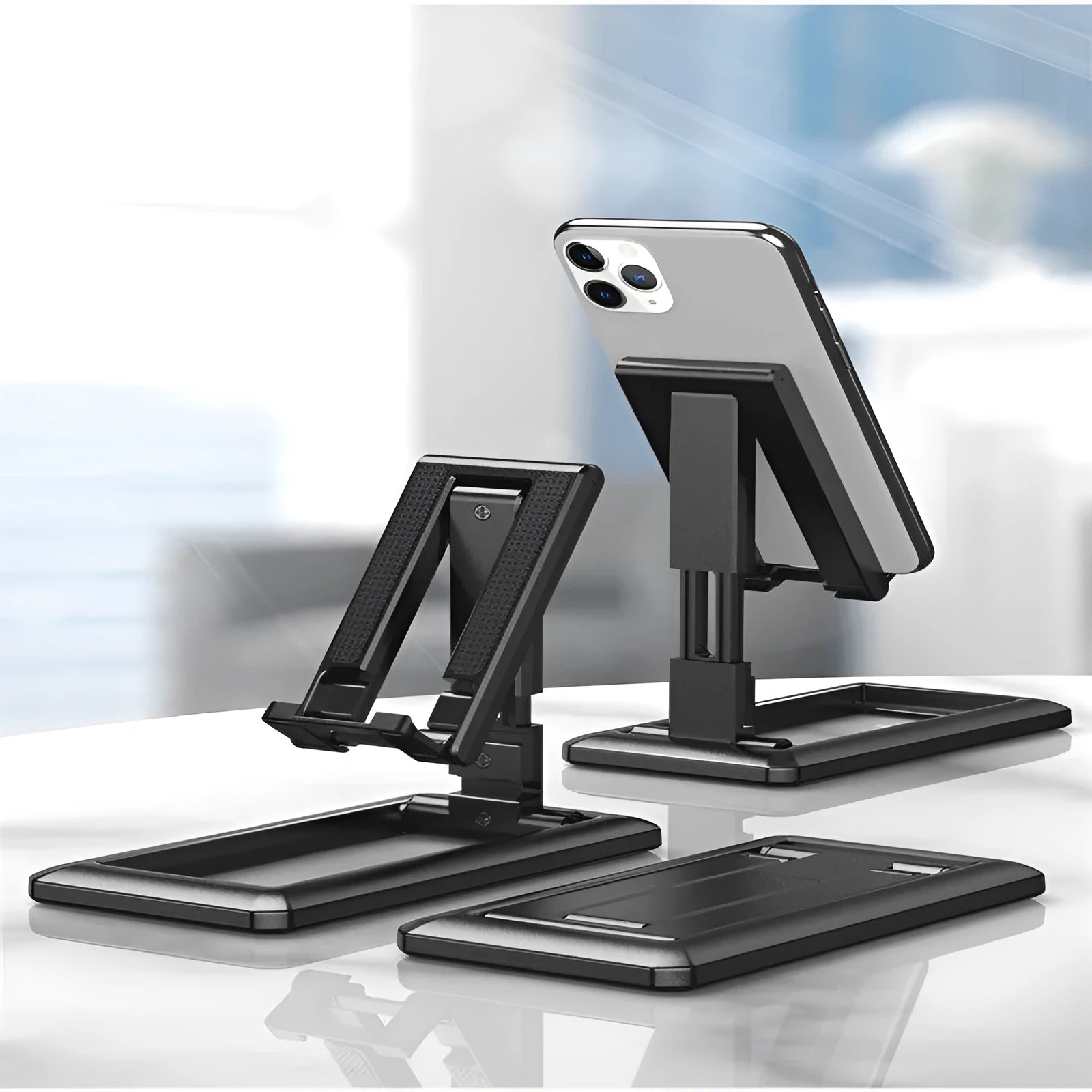 A retractable, foldable mobile phone desktop stand in an extended position, holding a smartphone.