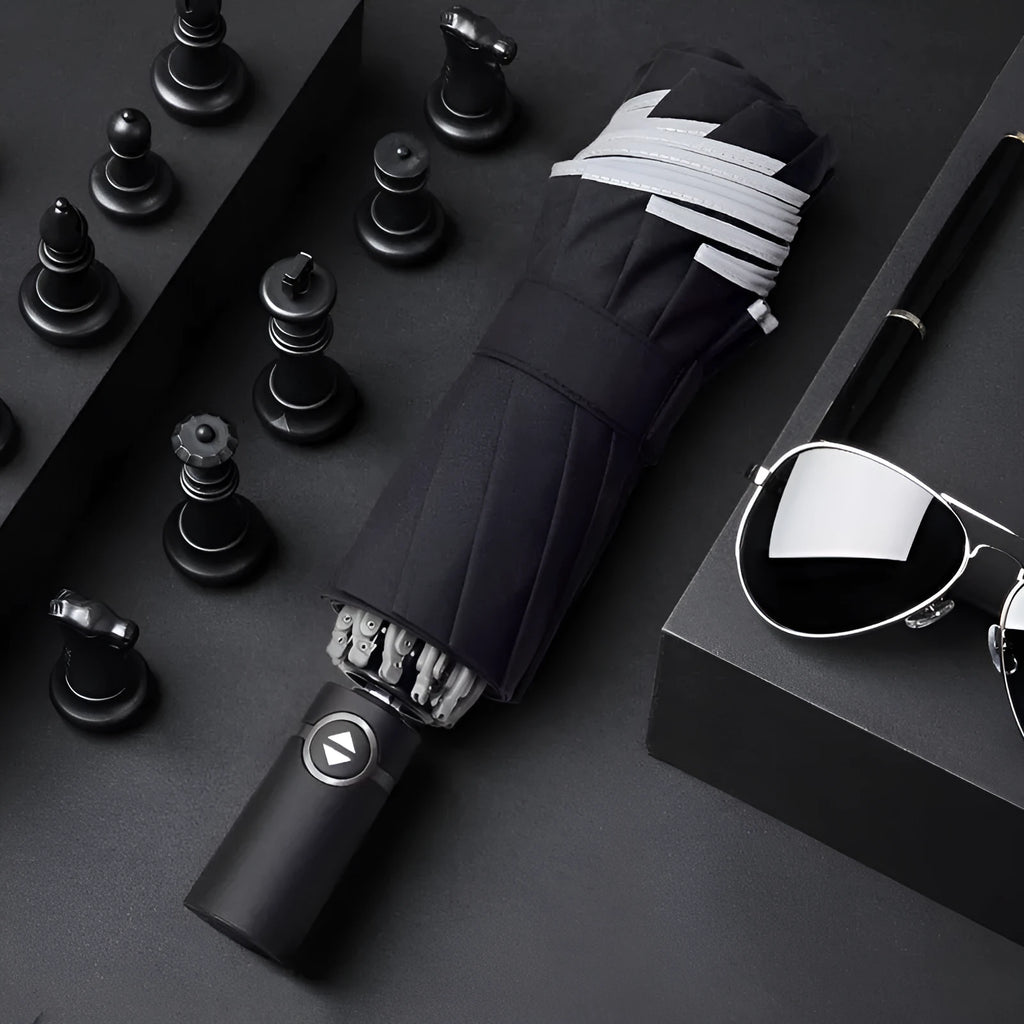 Black automatic reverse folding umbrella with plastic handle, shown closed and demonstrating the reverse mechanism.
