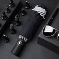 Black automatic reverse folding umbrella with plastic handle, shown closed and demonstrating the reverse mechanism.