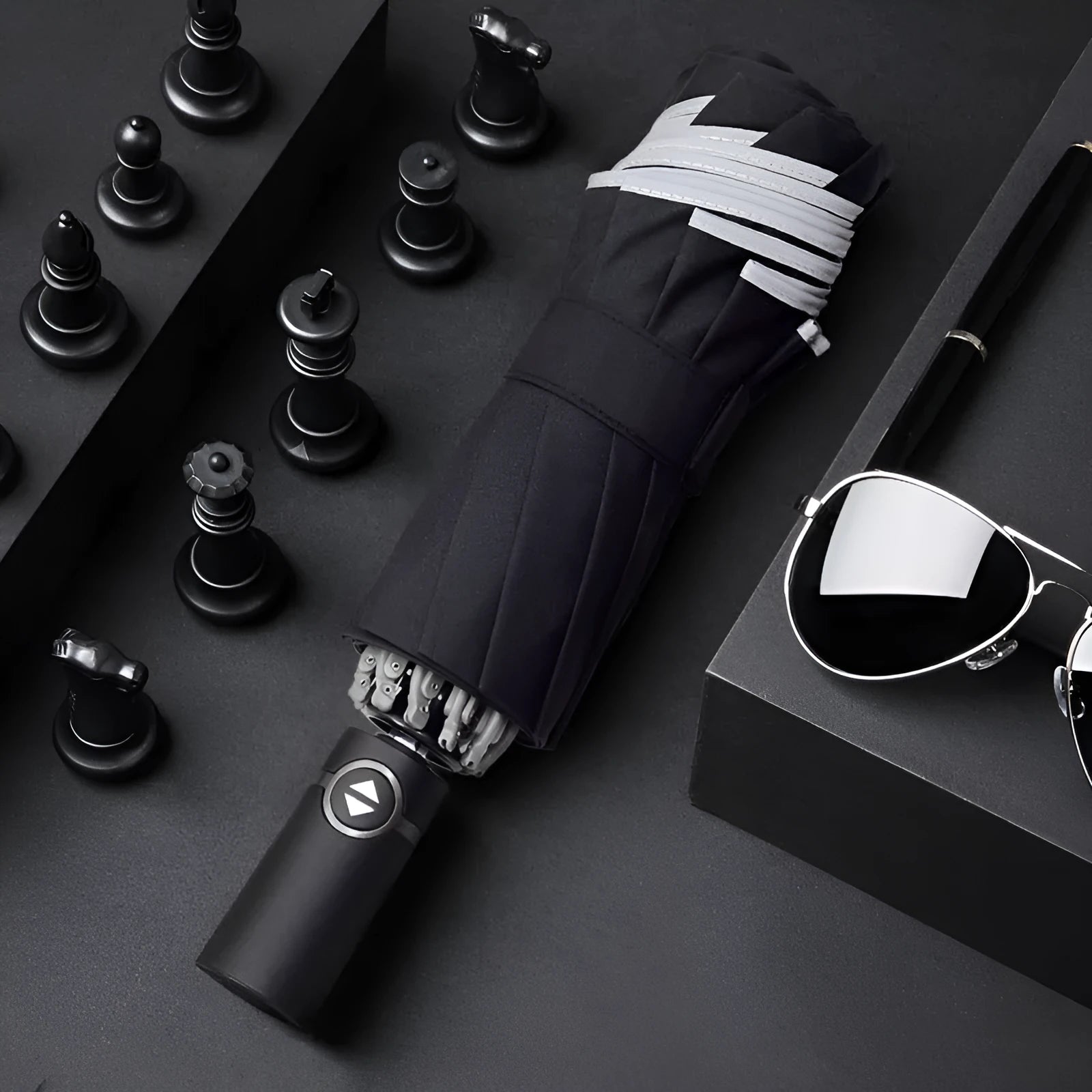 Black automatic reverse folding umbrella with plastic handle, shown closed and demonstrating the reverse mechanism.