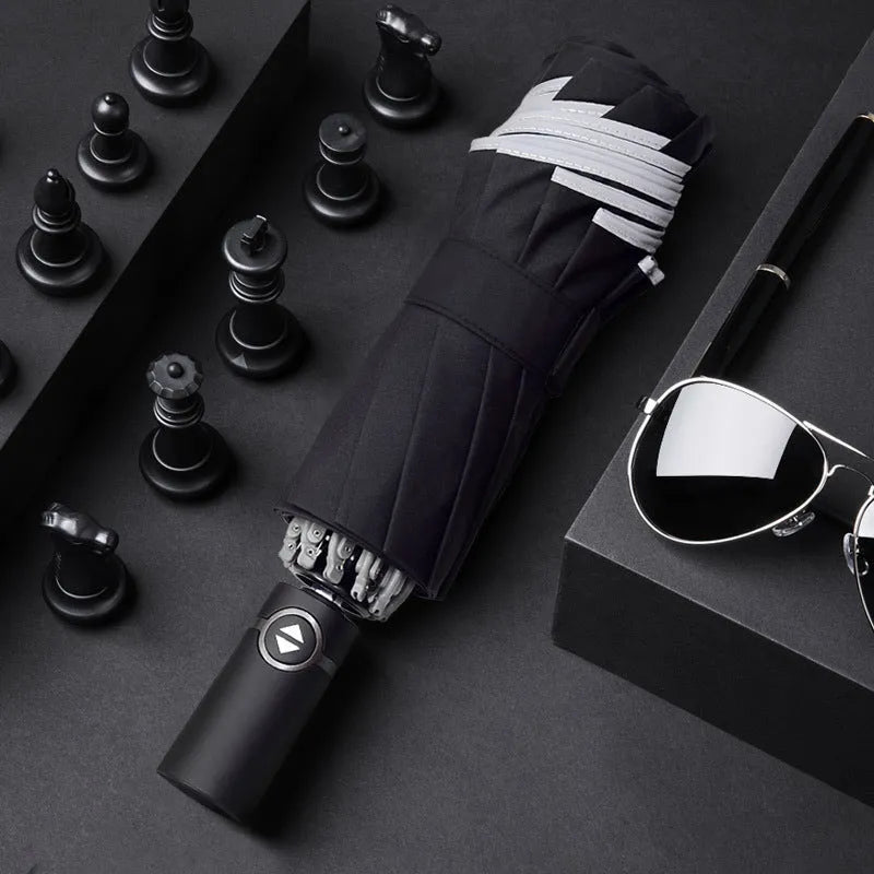 Black automatic reverse folding umbrella with plastic handle, shown closed and demonstrating the reverse mechanism.