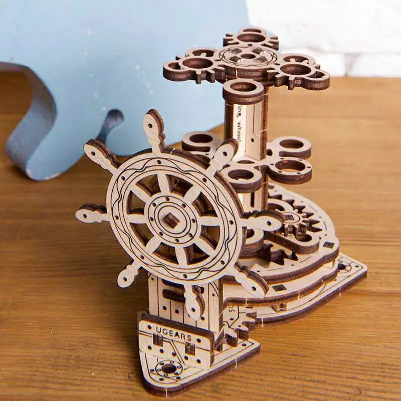 Wooden rotating pen holder with a turning steering wheel model on a desk.