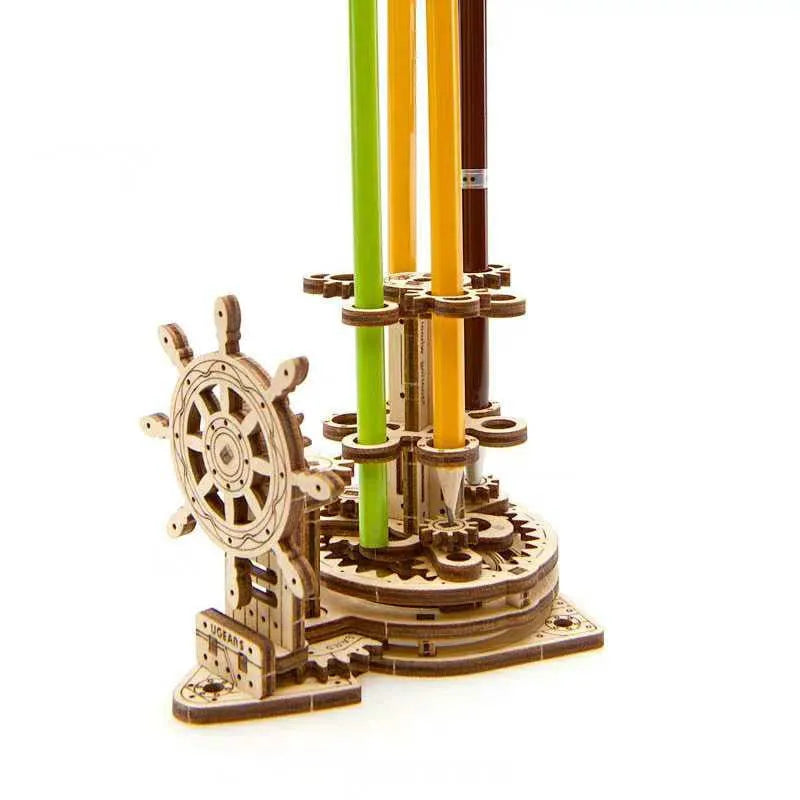 Wooden rotating pen holder with a turning steering wheel model on a desk.