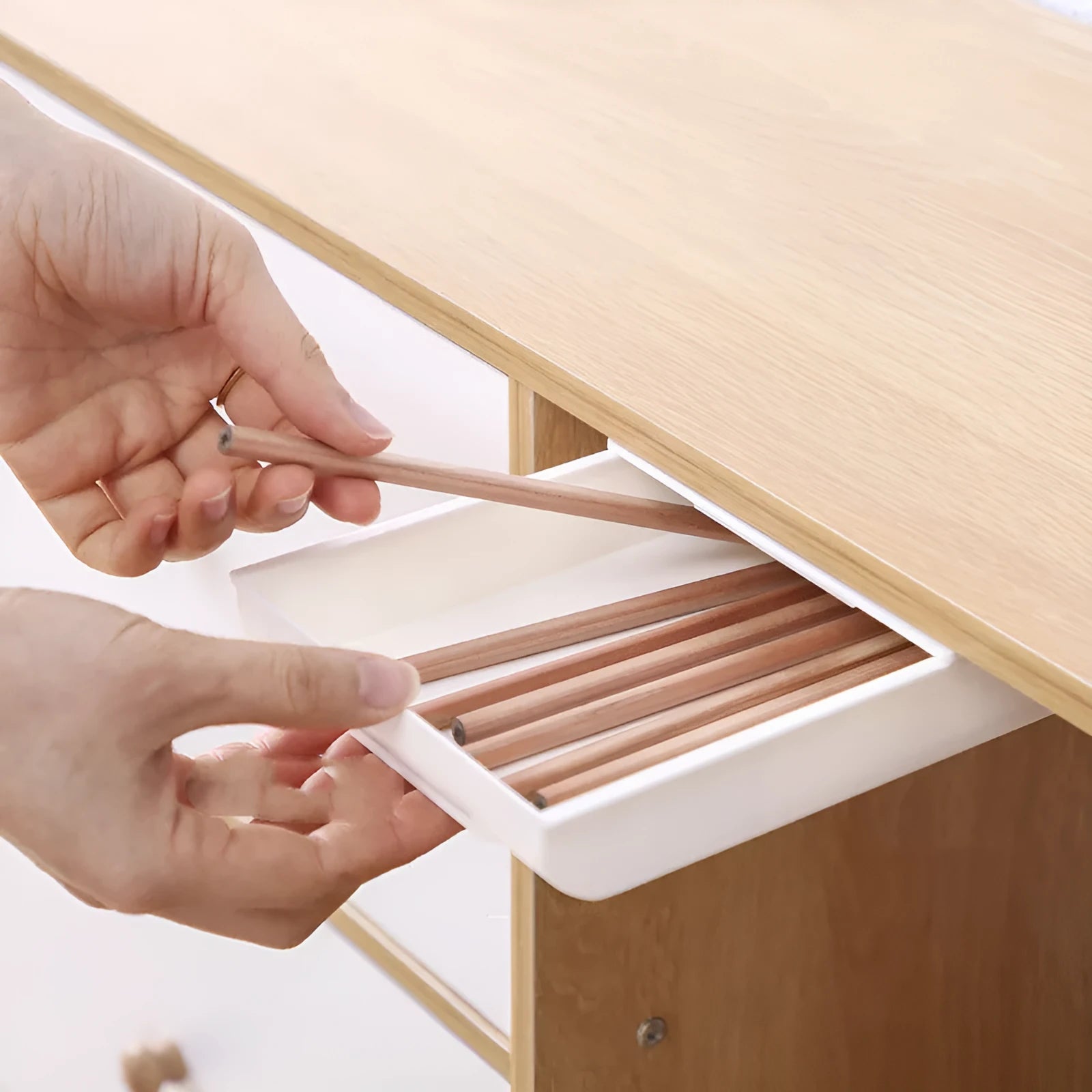 Japanese style plastic drawer storage box in grey placed under a table with stationery organised inside