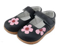A child's black leather princess shoe with embroidery and a Velcro strap fastener.