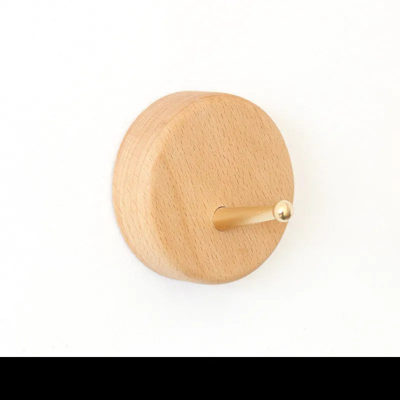 Beech wood and brass adhesive wall hook in one of five shapes: round, capsule, oval, diamond, or square.