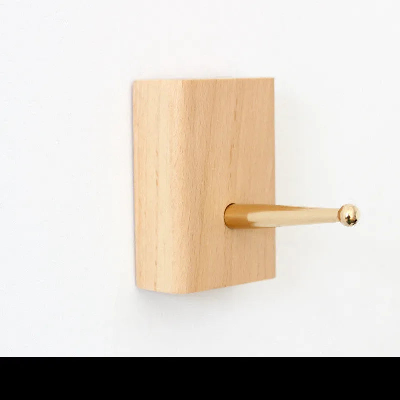 Beech wood and brass adhesive wall hook in one of five shapes: round, capsule, oval, diamond, or square.