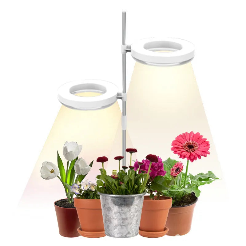 A compact LED plant growth light with a double-headed design, resting beside a small potted plant on a desk.