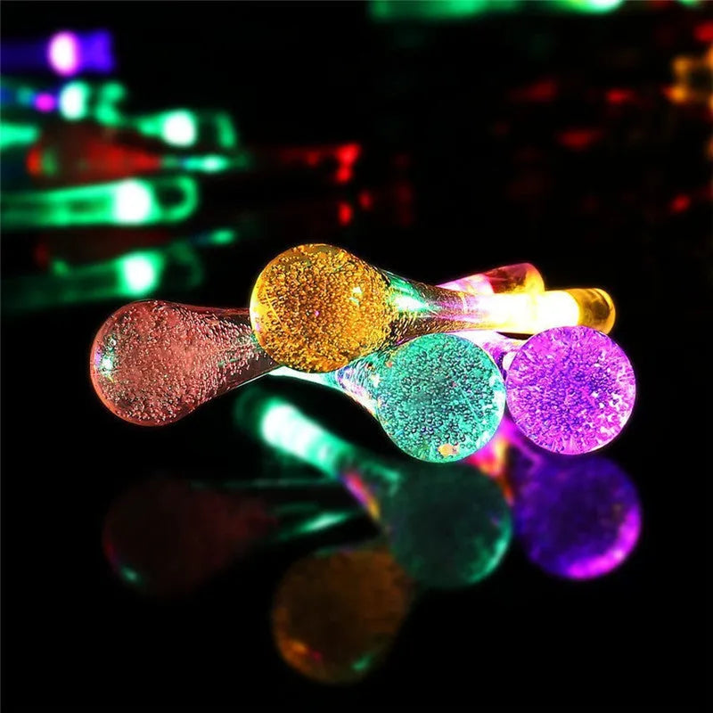 6.5 metre long solar-powered outdoor LED string lights with bubble drop pendants on a garden fence