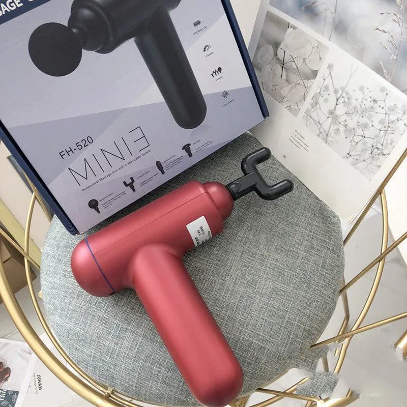 A grey handheld fascia gun muscle massager on a plain background.