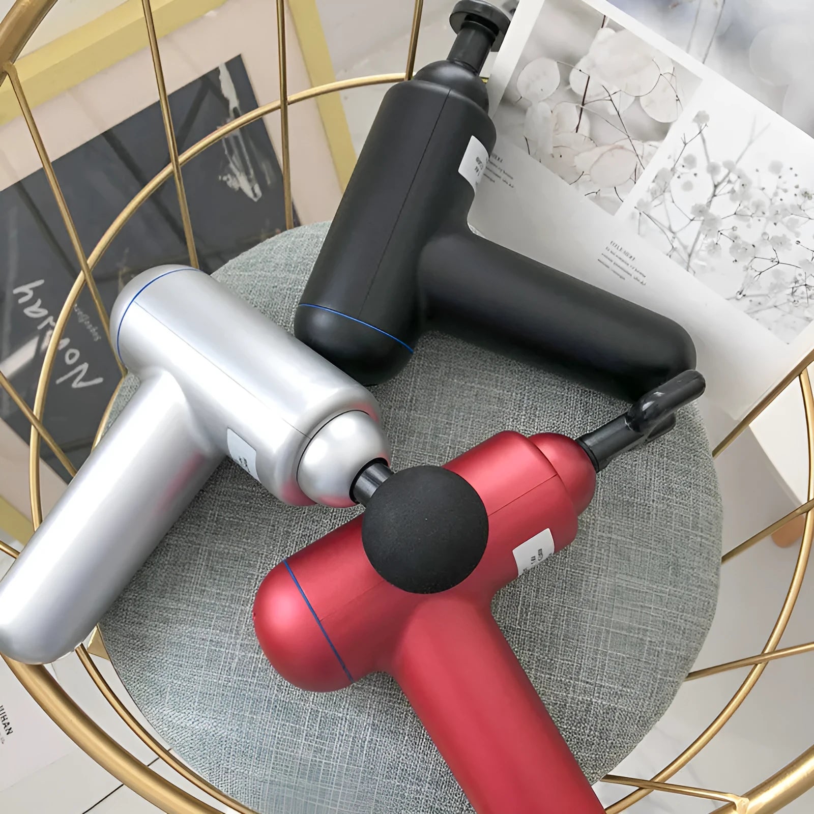 A grey handheld fascia gun muscle massager on a plain background.