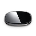 Black 15W Qi wireless fast charger with zinc alloy frame and glass top on a desk.