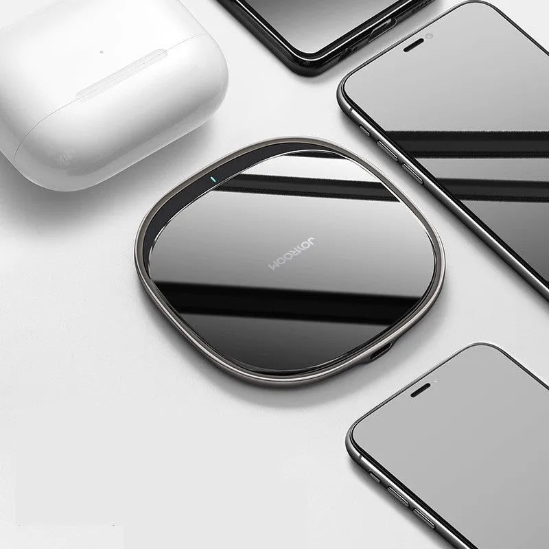 Black 15W Qi wireless fast charger with zinc alloy frame and glass top on a desk.