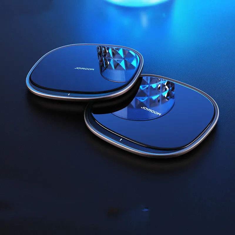 Black 15W Qi wireless fast charger with zinc alloy frame and glass top on a desk.