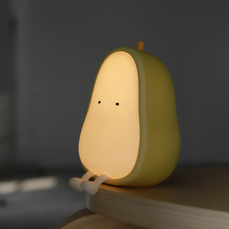 Pear-shaped silicone night light with warm yellow glow on a bedside table.