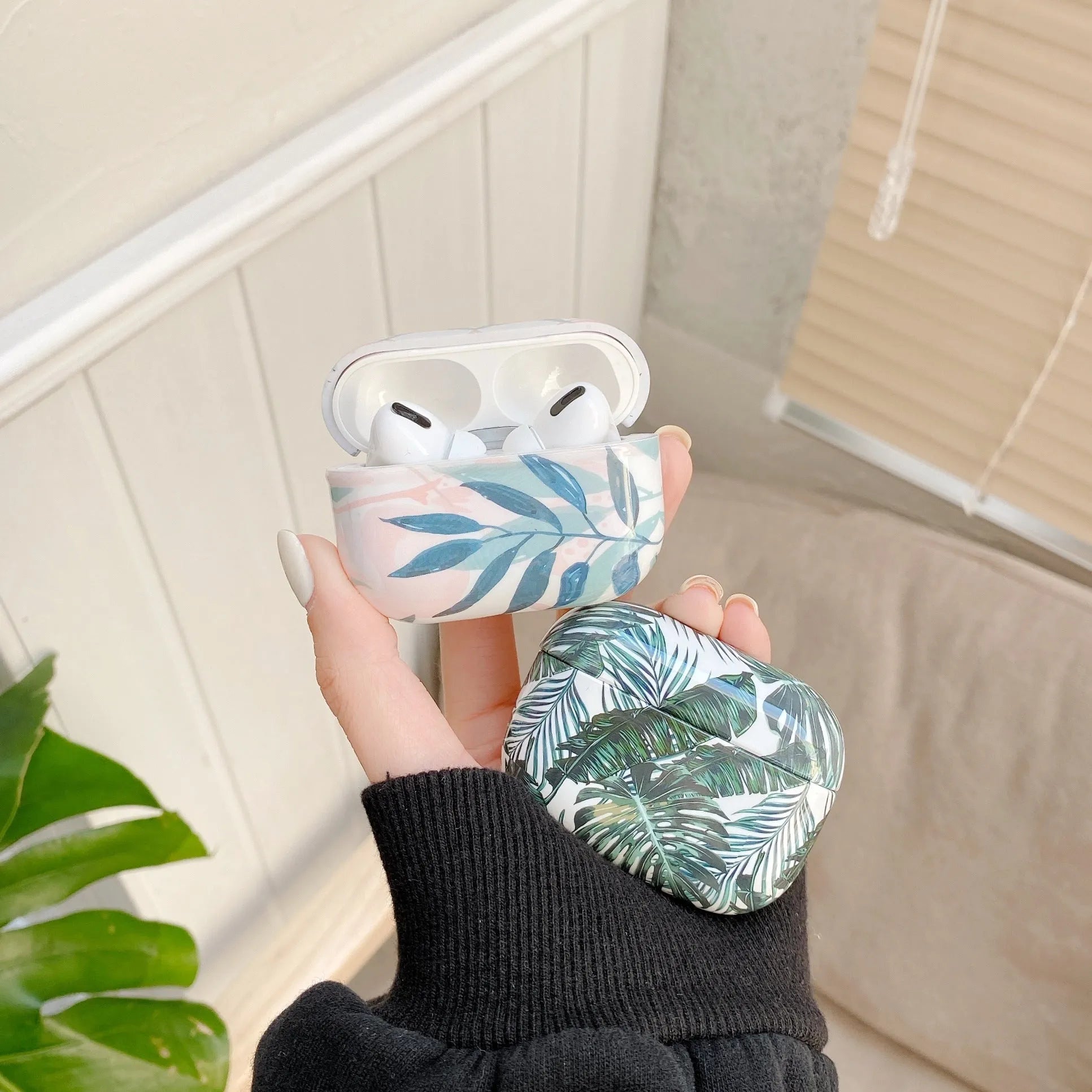 AirPods case with blue and green banana leaf tropical pattern on a TPU protective cover.