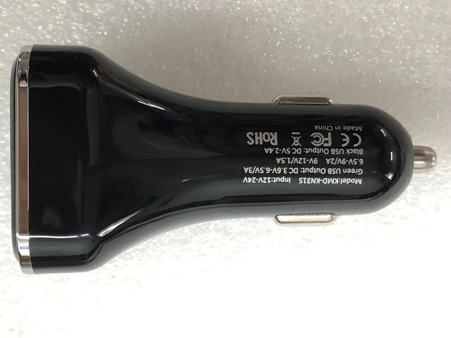 Black car charger with digital display showing voltage and current readings, dual USB ports