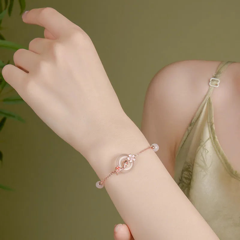 Close-up of a women's S925 sterling silver bracelet with a floral geometric shape, white chalcedony crystal, and a detailed Koi fish motif.