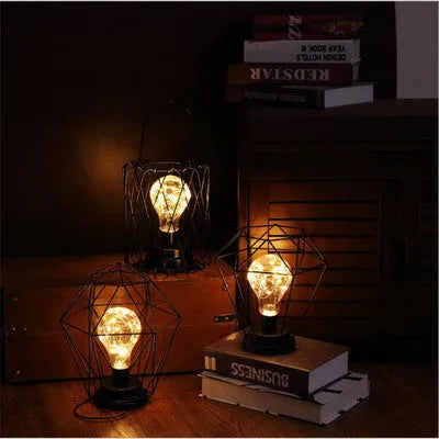 Minimalist hollow wrought iron table lamp in red wine bottle shape with warm white light on a desk