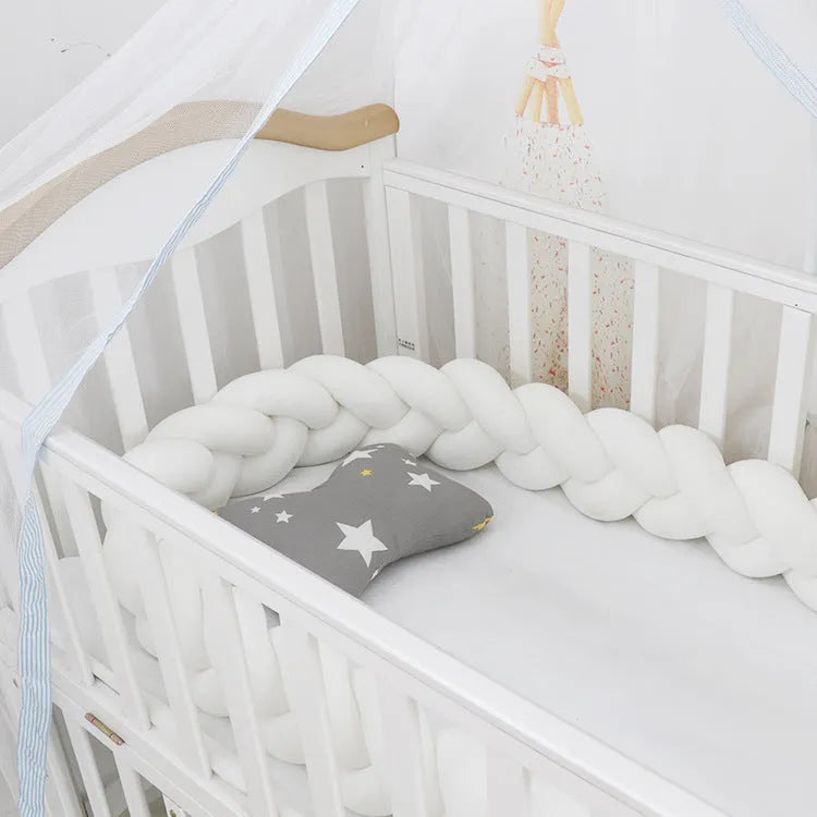 Bendable braid knot baby crib bumper in spandex velvet fabric on a white cot.
