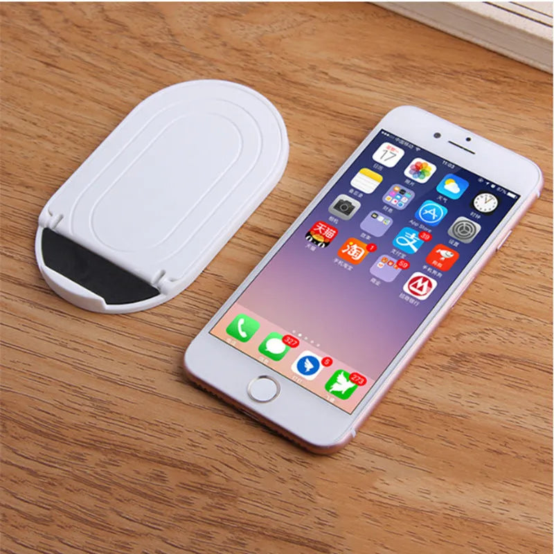 Adjustable plastic mobile phone stand in one of six colour options: black, blue, grey, pink, white, or yellow.