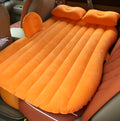 Universal inflatable car air mattress with flocked surface and pillows inside a vehicle.
