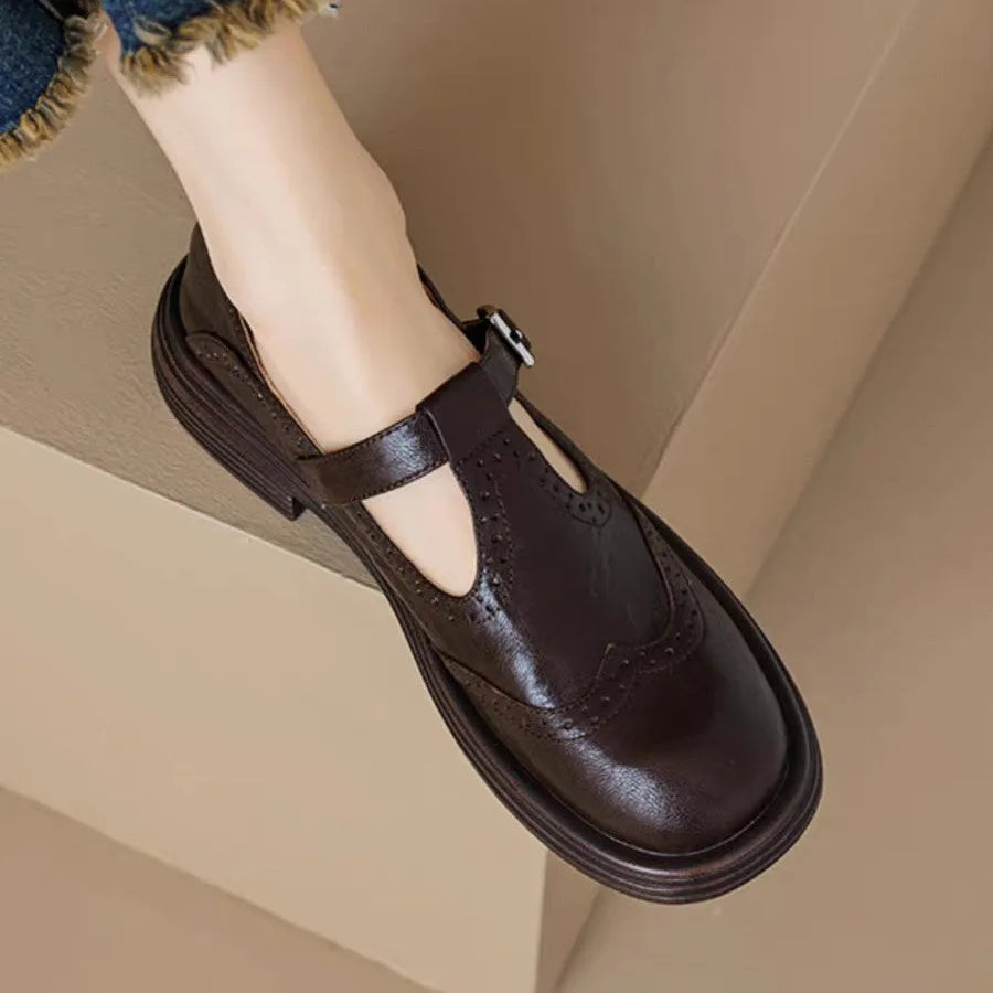Women's black British style leather flat shoe with round toe and slip-on design on a neutral background.