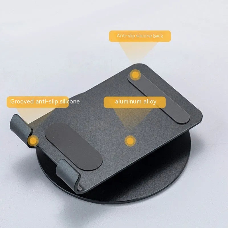 Grey aluminium alloy rotating mobile phone bracket on desk with silica gel grip, 4.8 x 4.2 x 1.4 cm, holding a smartphone in landscape mode