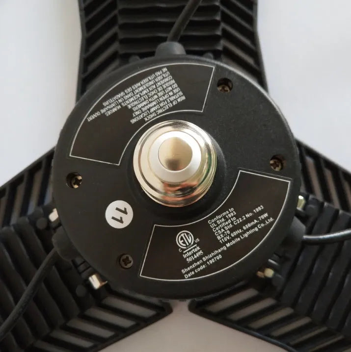 A foldable silver aluminium garage work lamp with a clear plastic lens, shown in an open position.