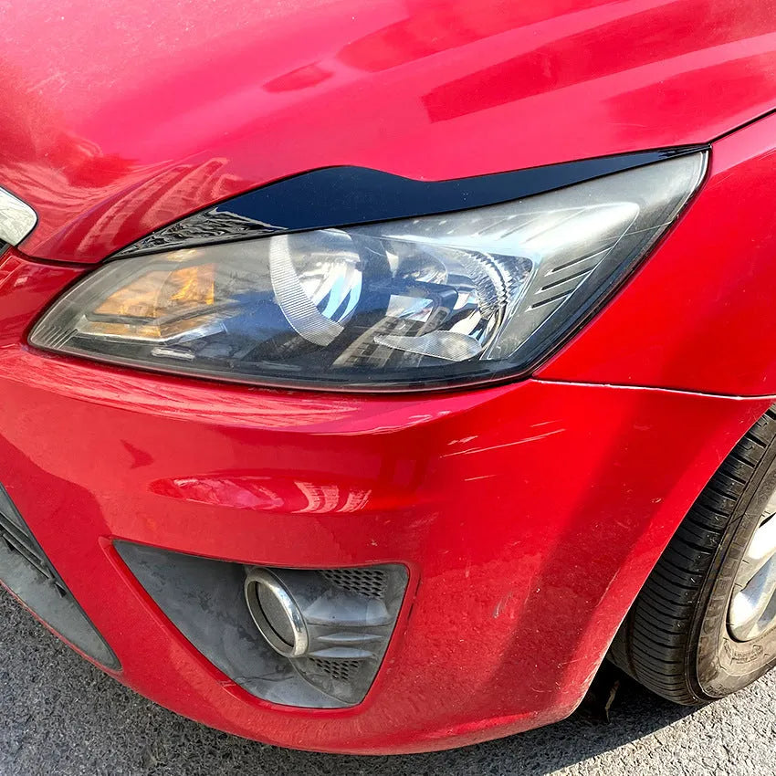 Two ABS plastic headlight eyebrow stickers for Ford Focus in carbon fibre and piano black finishes.