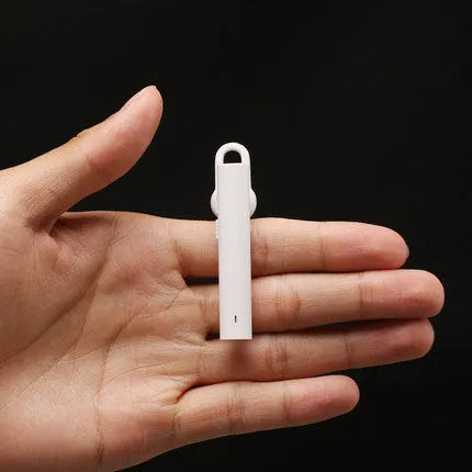 Compact black and white wireless Bluetooth headset for hands-free calls, shown next to a size scale.